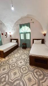 a bedroom with two beds and a carpet at Beit El-Abd Valley of Queens View in Al Aqālitah +17 photos