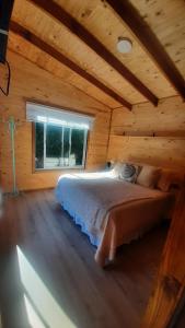 a bedroom with a bed in a log cabin at La Cabana de Cocholgüe 45 in Tomé
