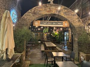a restaurant with a stone archway with tables and benches at Casa Lounge Xacobeo in Treacastela