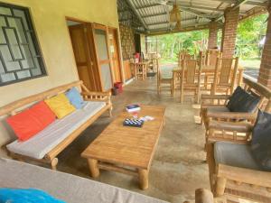 a porch with wooden furniture and tables and chairs at Dragon's Garden Dormitorio in Santa Cruz