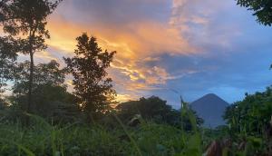 a sunset with a mountain in the background at Dragon's Garden Dormitorio in Santa Cruz