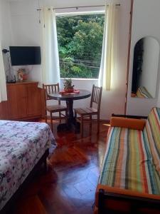 1 dormitorio con mesa, sillas y ventana en Apartamento aconchegante na serra!, en Miguel Pereira