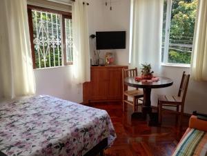 Un dormitorio con una cama, una mesa y un televisor. en Apartamento aconchegante na serra!, en Miguel Pereira