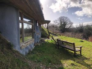 a bench sitting outside of a house in the grass at Rabbits 1or 2 bedroom hobbit style hillset earthen dartmoor eco home in South Brent