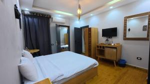 a bedroom with a white bed and a television at Hostalio Pyramid View in Cairo