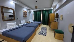 a hotel room with two beds and a television at Hostalio Pyramid View in Cairo +76 photos