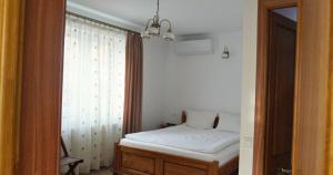 une petite chambre avec un lit et une fenêtre dans l'établissement Casa Coralis, à Călimăneşti