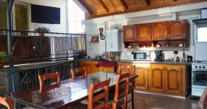 une cuisine avec des armoires en bois et une table et des chaises dans l'établissement Casa Coralis, à Călimăneşti