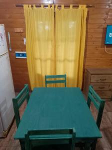a green table with two chairs and a yellow curtain at Brisas in Jardín América