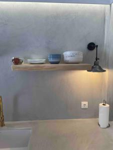 a shelf on a wall with bowls and a lamp at Relax with a view in Batsi