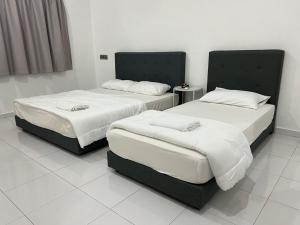two beds in a room with white floors at M Guest House2 in Muar