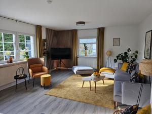 ein Wohnzimmer mit Sofa, Sesseln und Fernseher in der Unterkunft Landhaus SoonZauber in Münchwald