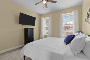 a bedroom with a white bed and a flat screen tv at Red Brick Hideaway in Soulard