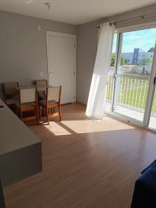 a living room with a table and chairs and a large window at Apartamento Umuharama in Pelotas +9 photos