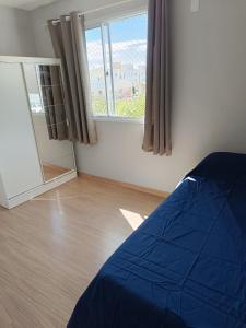 a bedroom with a blue bed and a window at Apartamento Umuharama in Pelotas +9 photos