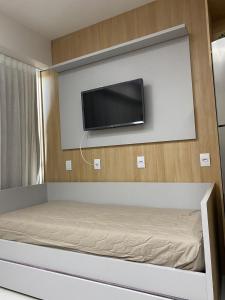 una camera da letto con un letto e una TV a parete di Flat makia 123 C acessivel a Ipojuca