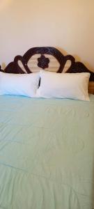 a green bed with a wooden headboard and white pillows at EsMash Homes Air,bnb Lanet Nakuru in Nakuru