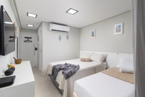 Una habitación blanca con dos camas y un espejo. en Design & Conforto Praia aos seus Pés Flats Mauê, en Tamandaré 12 fotos más