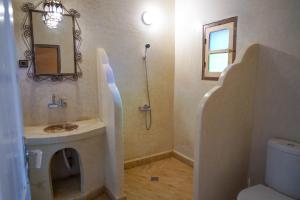 Un baño con lavabo, inodoro y espejo. en Kasbah Erg Chebbi, en Merzouga