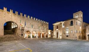 a large stone building with a clock tower at night at La Dimora del Borgo in Montecassiano