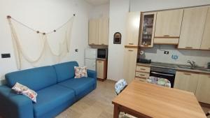 a living room with a blue couch and a kitchen at Il pescou, accogliente bilocale in Savona