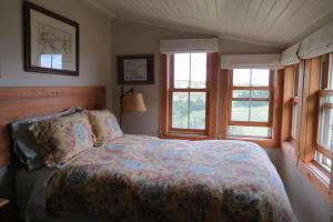 a bedroom with a bed and two windows at Devil's Cove in Port Rexton
