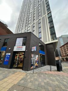 a tall building with a store in front of it at Cozy City Centre Apartment with Free Gym and Free Coffee in Birmingham