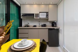 una cocina con una mesa amarilla con una taza. en Design & Conforto Praia aos seus Pés Flats Mauê, en Tamandaré