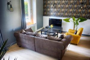 a living room with a brown couch and a fireplace at chez joseph , appartements renovés et au calme à saint-michel in Saint-Brieuc