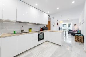 a kitchen with white cabinets and a living room at Mi Casa es Tu Casa - Malaga Center - Fiber WiFi in Málaga