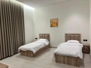 two twin beds in a room with curtains at new Luxury Apartment near Masjid Quba in Al Madinah