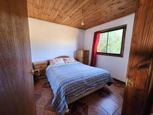 a small bedroom with a bed and a window at House, airport side in Pucón
