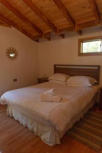 1 dormitorio con 1 cama blanca grande y ventana en Cascadas del Llaima, en Refugio Llaima