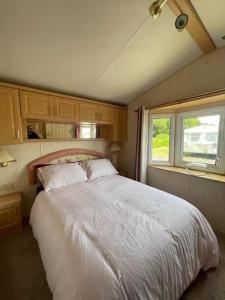 a bedroom with a large white bed with two windows at 6 Berth Caravan Skegness Highfields and the Haven in Winthorpe