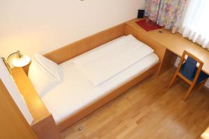 a small bed in a room with a desk at Gasthof Bokan in Graz
