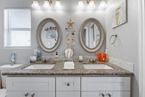 a bathroom with two sinks and two mirrors at 4BR w Hot Tub Gameroom OceanView by Bolivar Vacations in Bolivar Peninsula +40 photos