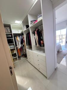 Elle comprend un dressing avec des tiroirs et des étagères blancs. dans l'établissement Casa da Mãe São Pedro, à São Pedro da Aldeia