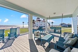 a porch with blue chairs and a table and the beach at Seaside Sunrise Luxury Beachfront, Hot Tub, Firepit, Elevator in Port Bolivar