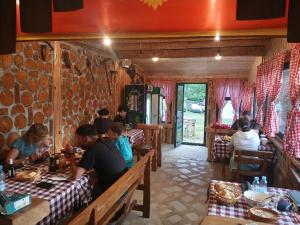 a group of people sitting at tables in a restaurant at Ethno Cottage Momo Tepca in Žabljak