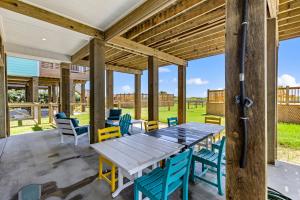 a patio with a wooden table and chairs at Wayward Sun Luxury 4BR Gulf Retreat w Pool, Hot Tub & Elevator in Port Bolivar