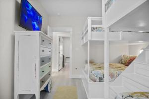 Port BolivarにあるLuxury 3BR Beach Cabin w Gulf Views and Soaking Tubの白いベッドルーム(ベッド1台、ドレッサー内のテレビ付)