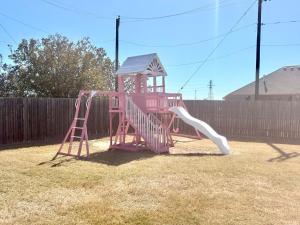a pink playset with a slide in a yard at Luxury 4br home, 2 king,1 queen, 3bed, 4tv in Wichita Falls