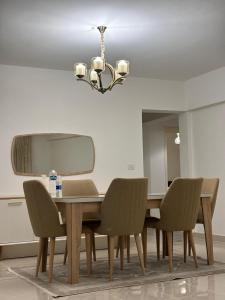 une table à manger avec des chaises et un lustre dans l'établissement fully furnished apartment with 3 Rooms & 3 Bath in Rehab City, à Burg el-Ḥudûd
