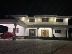a white house with a red car in front of it at The White House in Thodupuzha