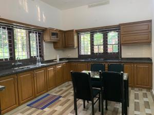 a kitchen with wooden cabinets and a table and chairs at The White House in Thodupuzha