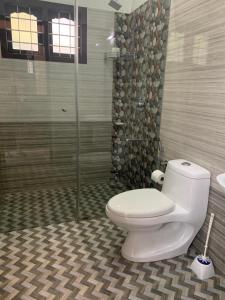 a bathroom with a toilet and a glass shower at The White House in Thodupuzha