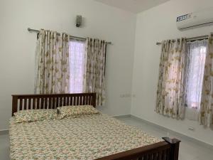 a bed in a room with windows with curtains at The White House in Thodupuzha