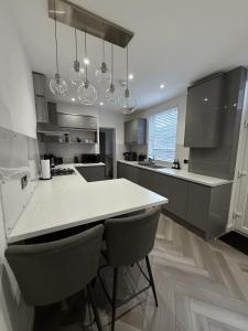 a kitchen with a white counter and chairs in it at A home away from home in Manchester