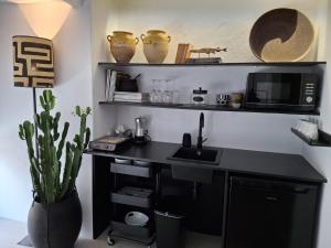 a kitchen with a desk with a sink and a microwave at casita en la playa in El Rompido +14 photos