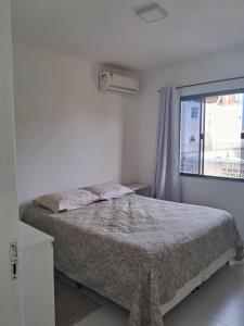 Una habitación blanca con una cama y una ventana en Acácia Jurerê, en Florianópolis